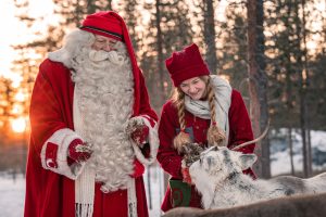 Santa Claus and an Elf feeding reindeer at Porovaara Hill reindeer farm in Rovaniemi, Lapland