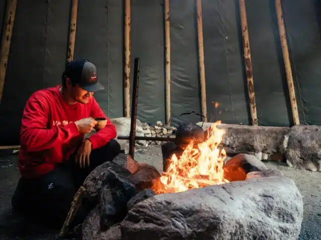 Reindeer guide beside a campfire in a traditional Lappish hut
